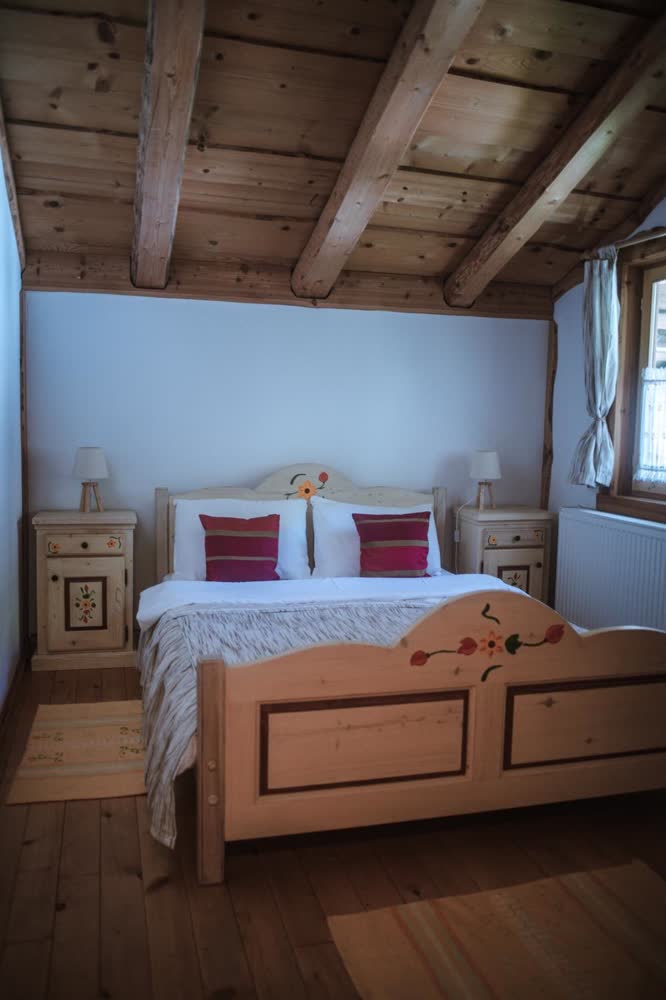 Dormitor la Cabana Bendis — pat dublu sub tavanul cu bârne.