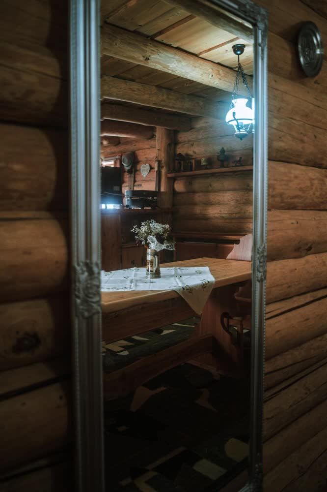 Livingul cabanei — oglinda care întoarce camera de bârne.